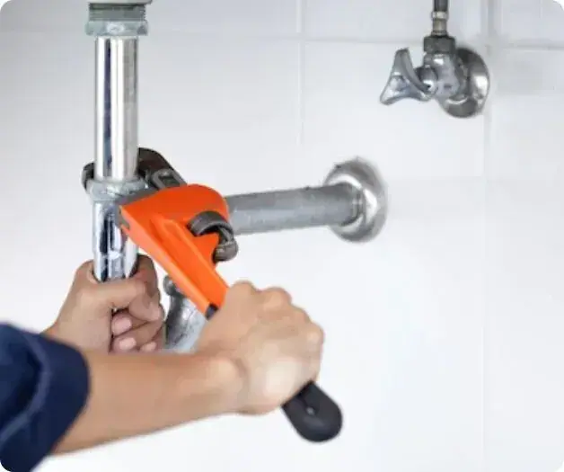 Installateur arbeitet mit einer Rohrzange an einer Leitung